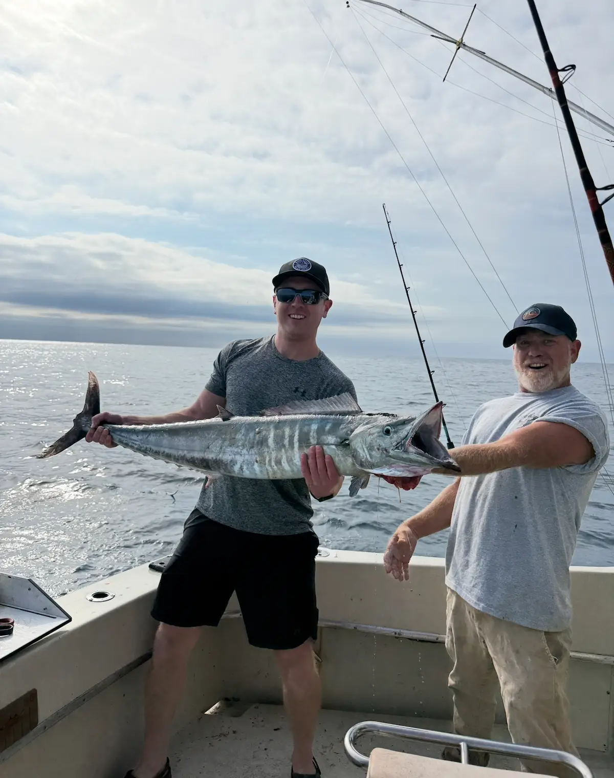 Father and son holding a large wahoo at sunset